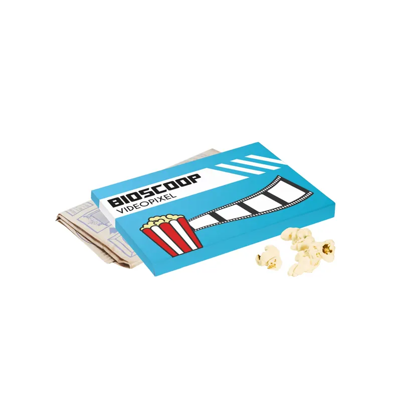 Blauw-wit bedrukte doos met Bioscoop Videopixel-opdruk, een papieren popcornzakje en losse popcorn op witte achtergrond.