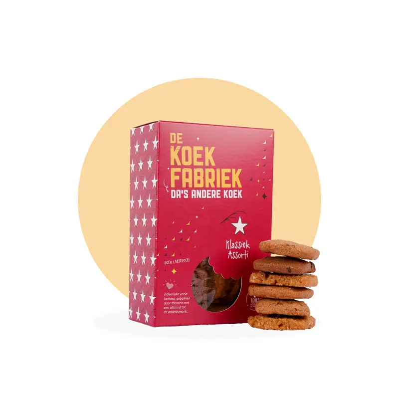 Rode kartonnen verpakking van De Koekfabriek Klassiek Assorti met witte sterren, een venster met koekjes en vijf gestapelde koekjes op een beige achtergrond.