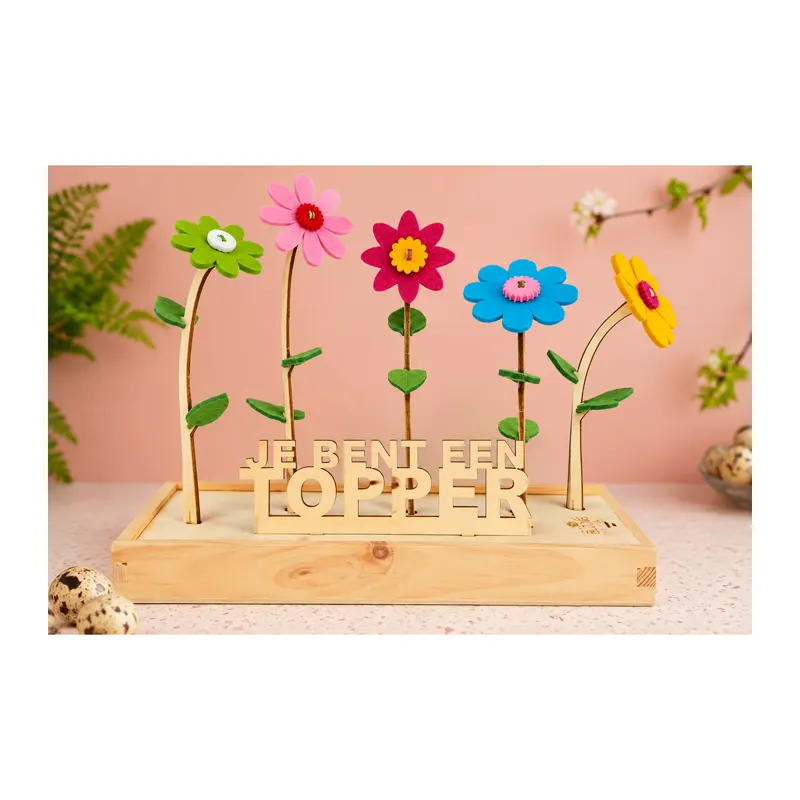 Vijf kleurrijke bloemen met vilten bloemblaadjes op houten stelen in een houten standaard met de tekst ‘Je bent een topper’.